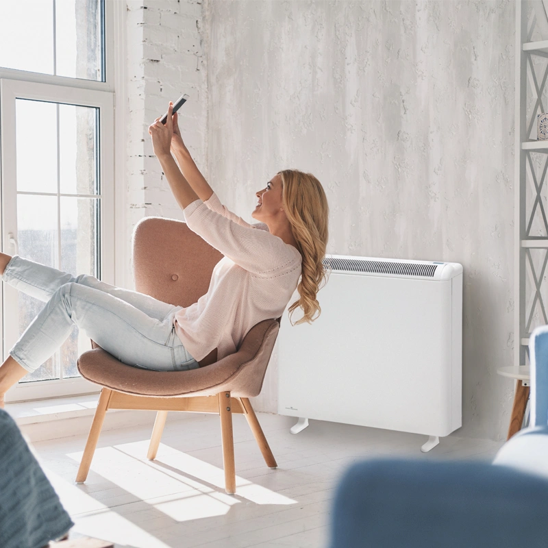 Elnur PROSSH158 Smart Storage Heater installed in flat. A woman is set in front of it smiling as she takes a selfie.