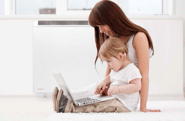 Woman and child playing on laptop, with Elnur PROSSH Smart Storage Heater installed behind her.